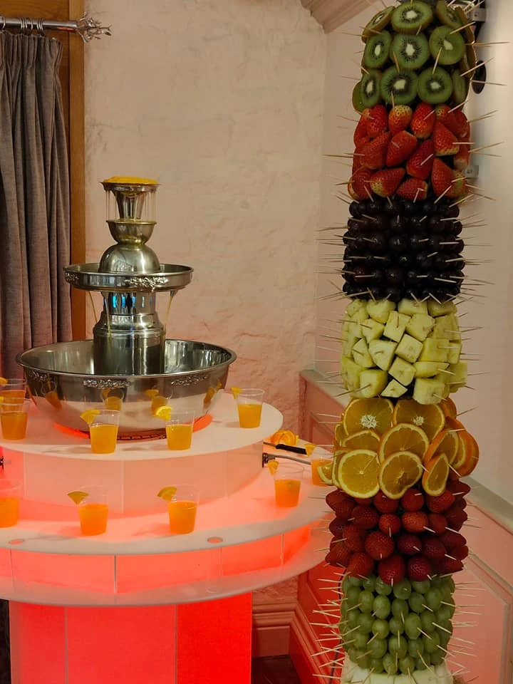 Chocolate fountain beside a fruit display tower