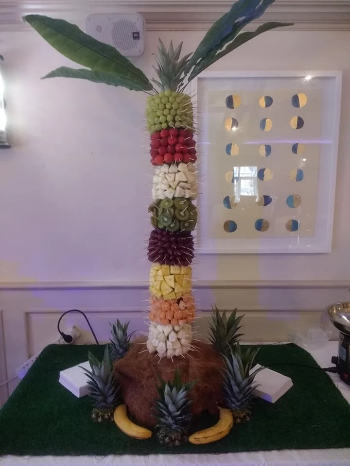 Fruit palm tree display beside a donut wall