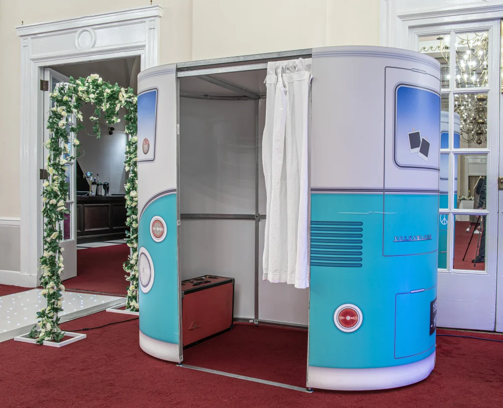 VW campervan photo booth beside a flower arch