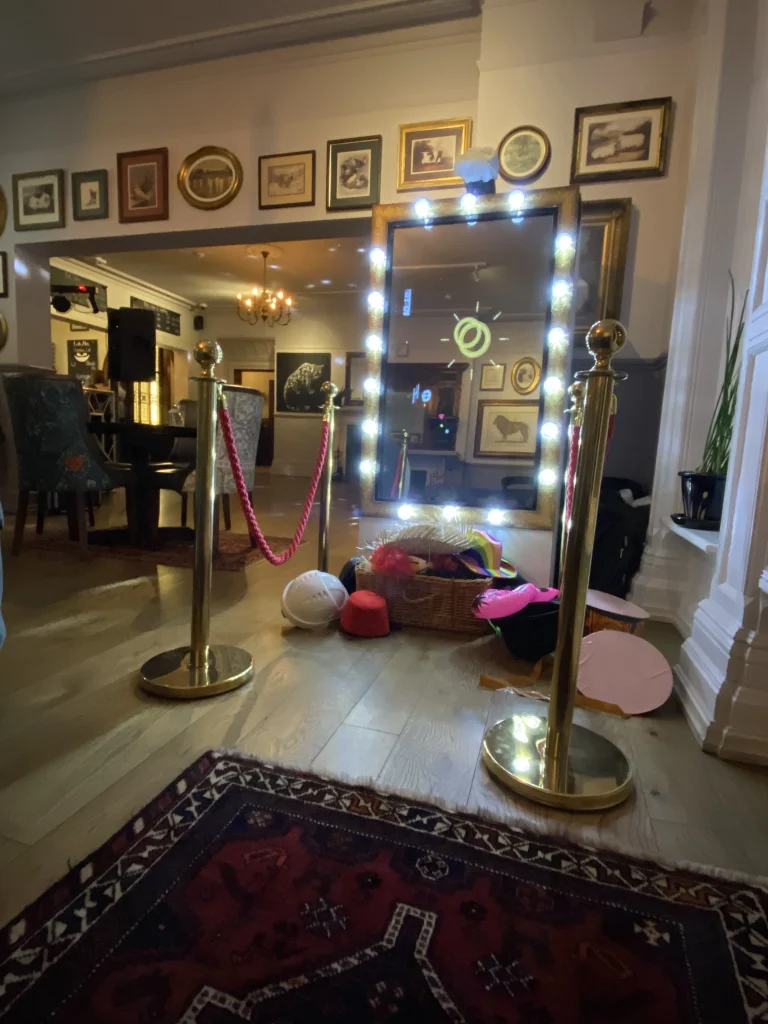 Selfie mirror photo booth with light-up frame set up at a venue