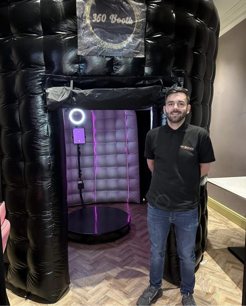Black inflatable photo booth with an attendant