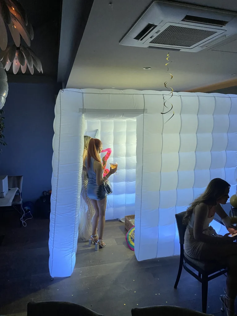 Guests using a white inflatable photo booth