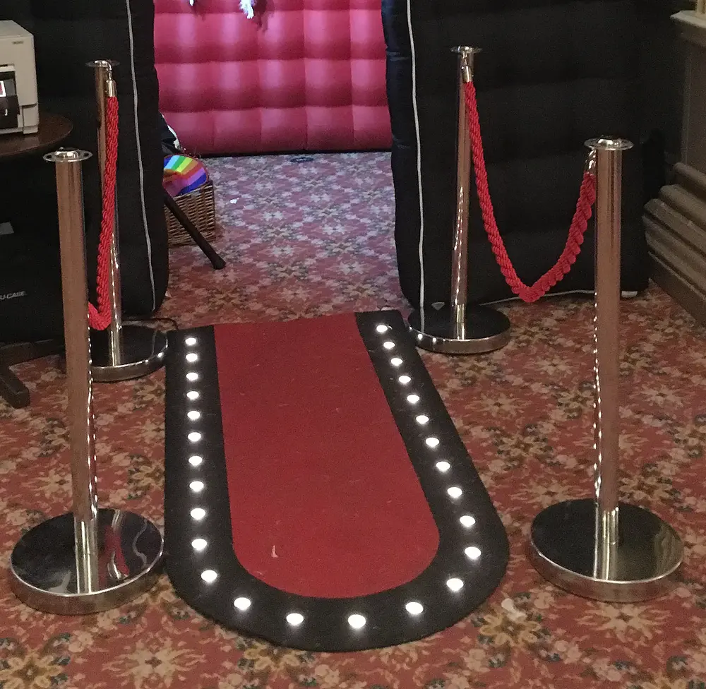 Red carpet with rope barriers and a light-up walkway